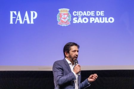 Imagem mostra Ricardo Nunes, homem branco, de cabelo e barba pretos, de terno azul, falando ao microfone - Metrópoles