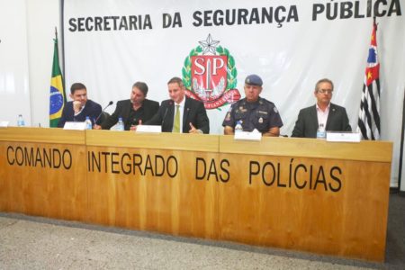 Imagem colorida mostra o secretário de segurança de São Paulo, Guilherme Derrite, no centro de uma mesa de cinco homens, integrantes da cúpula da segurança do estado - Metrópoles