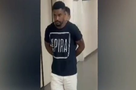 Foto colorida mostra suspeito preso