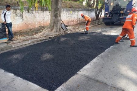 imagem colorida mostra rua com operários trabalhando no reparo de parte do piso com asfalto novo - Metrópoles