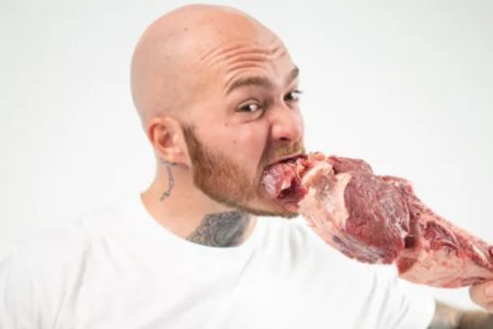 Foto colorida de um homem segurando uma carne crua - Metrópoles