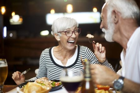 Foto de casal de idosos comendo e sorrindo - Metrópoles