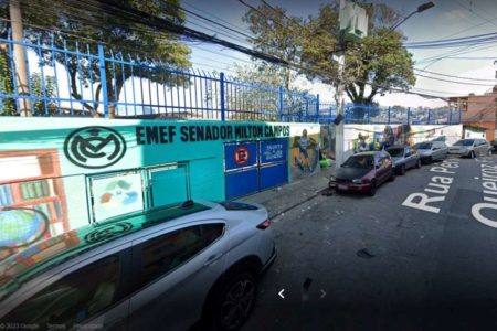 Imagem colorida da entrada da escola pública. Muro tem grafites pintados e é protegido com cerca em cima - Metrópoles