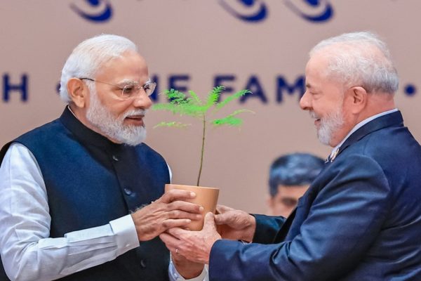 Foto colorida de Luiz Inácio Lula da Silva, durante G20, na Índia. Ele recebe martelo de madeira do premiê indiano, Narendra Modi