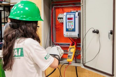 Foto colorida de pessoas de uniforme mexendo em quadro de energia - metrópoles