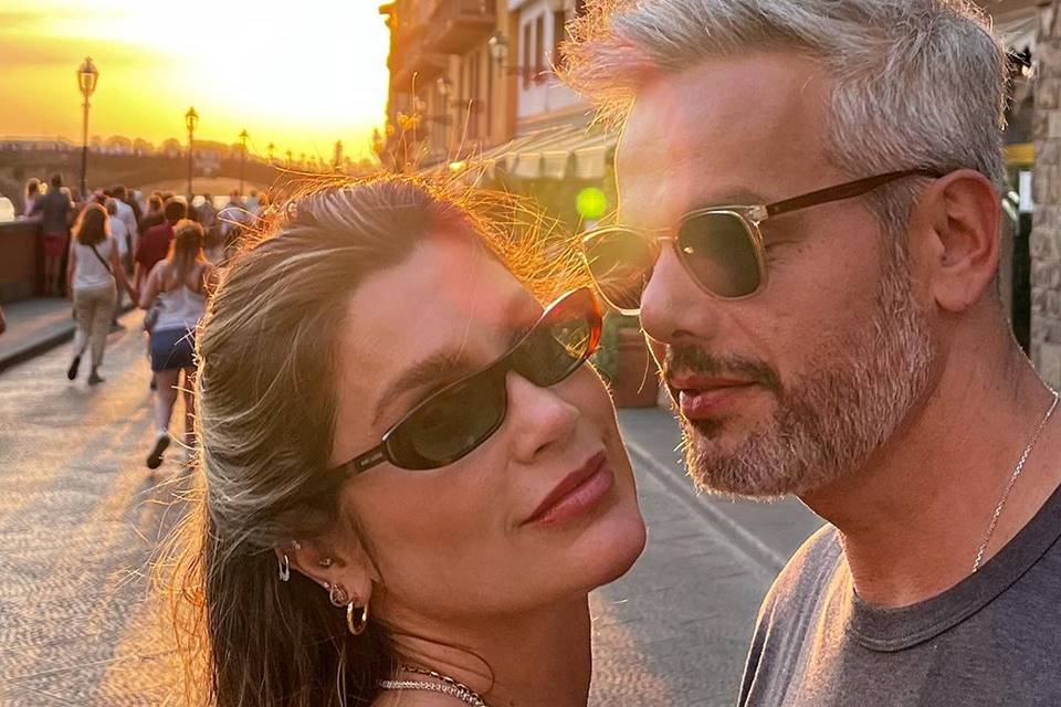 Foto colorida em close do casal Flávia Alessandra e Otaviano Costa de óculos escuros com o pôr do sol ao fundo - Metrópoles