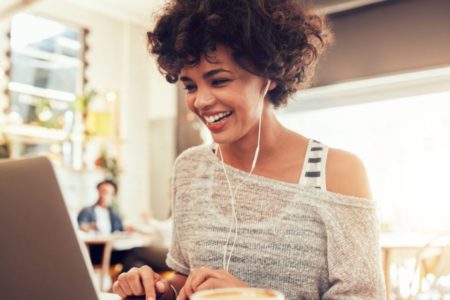 mulher em frente ao computador com fones de ouvidos, emprego - Metrópoles