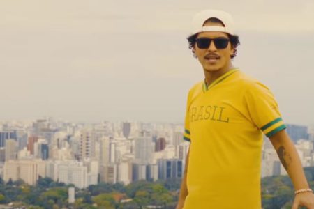 Imagem colorida do cantor bruno mars usando boné branco óculos escuro e camiseta amarela - metrópoles