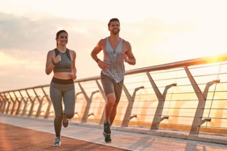 Casal correndo ao por do sol em uma ponte - Metrópoles - Corrida