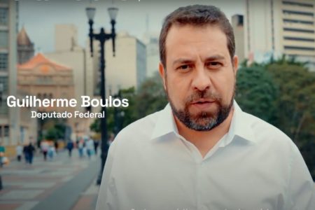 Imagem colorida mostra frame de propaganda com Guilherme Boulos, homem branco, de cabelo e barba castanhos, camisa branca, andando no viaduto Santa Ifigênia, em São Paulo - Metrópoles