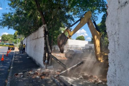 muro destruído com escavadeira ao lado