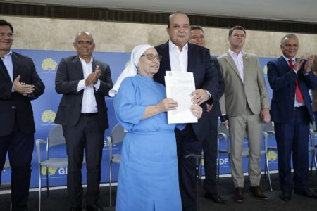 Mulher vestida de freira ao lado de homem careca de terno preto