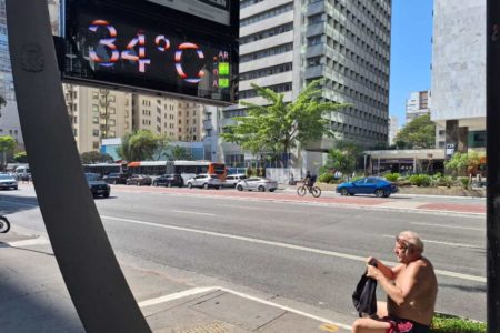 foto colorida de homem sentindo calor sem camisa na Avenida Paulista, perto de termômetro que marca 34 graus - Metrópoles