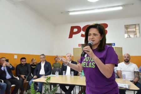 Imagem colorida mostra Lúcia França, mulher discursando ao microfone - Metrópoles