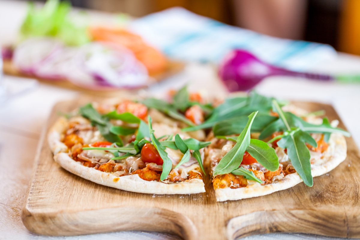 Pizza caseira em tábua de madeira em uma mesa - Metrópoles