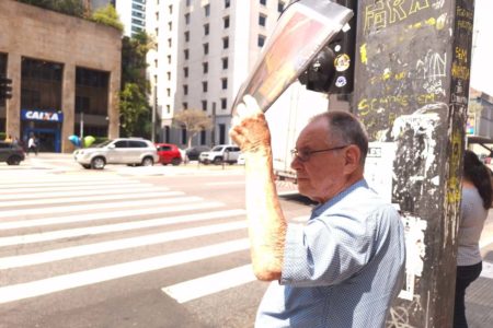 foto colorida mostra idoso se protegendo do sol e do calor com jornal em trecho da Avenida Paulista - Metrópoles