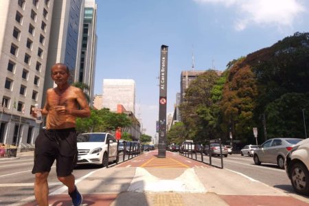 foto colorida mostra idoso correndo sob o sol em trecho da Avenida Paulista - Metrópoles