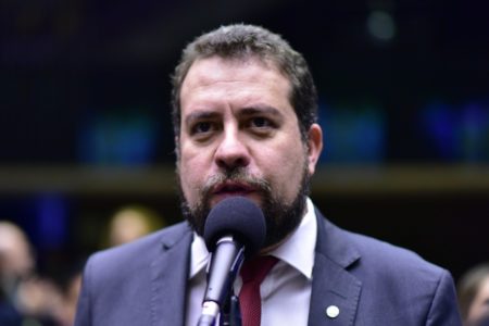 Imagem colorida mostra Guilherme Boulos, dos ombros para cima, de terno e gravata, falando ao microfone no Congresso - Metrópoles