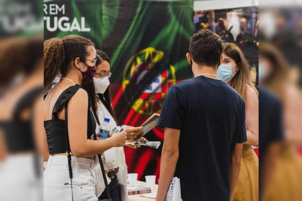 Quatro estudantes reunidos em frente a uma bandeira de Portugal segurando panfletos do salão e das instituições