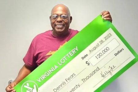 Fotografia colorida de homem segurando cheque de US$ 120 mil após apostar no mesmo número em 24 bilhetes na loteria