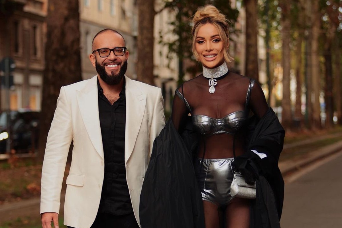 Foto colorida de homem pardo e blazer branco ao lado de mulher branca, loira com roupa prateada - Metrópoles