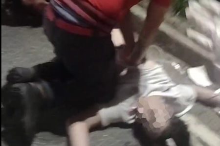 Em foto colorida bombeiro civil faz massagem cardíaca em jovem de amisera branca caído na rua - Metrópoles