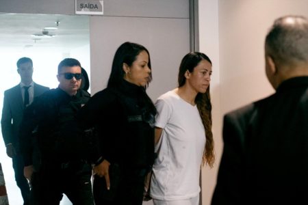 Foto de Ana Priscila Azevedo chegando, algemada e de branco, na Câmara Legislativa