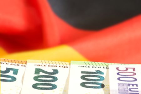 Imagem colorida de notas de euro e, ao fundo, a bandeira da Alemanha - Metrópoles