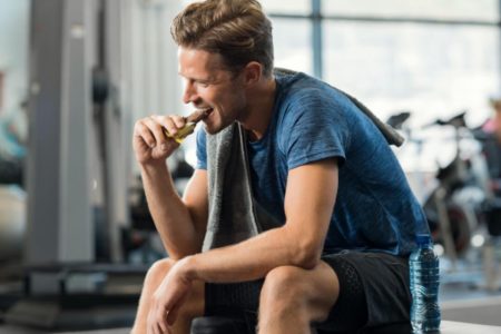 Homem na academia comendo barrinha de cereal