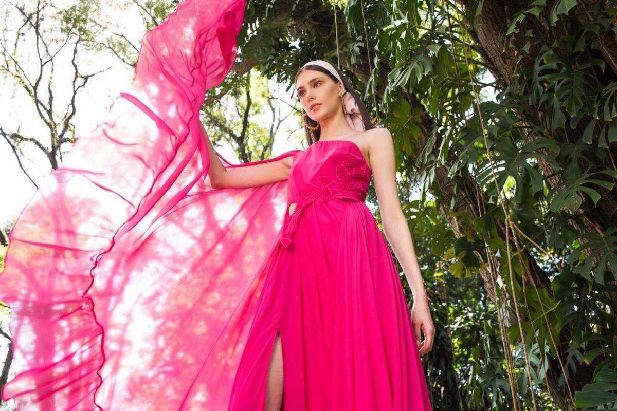 Em fundo de plantas, modelo usa vestido rosa esvoaçante - Metrópoles