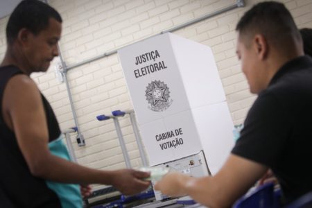 mulher entregando documento em fila de votação