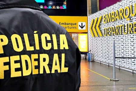 Imagem colorida de agente da polícia federal de costas no aeroporto internacional de são paulo em guarulhos - Metrópoles