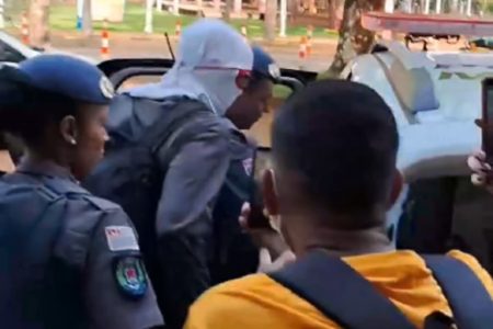 Imagem colorida mostra homem encapuzado sendo colocado em viatura da polícia. Ele é um professor da Unicamp, que ameaçou um aluno com uma faca dentro do campus da instituição - Metrópoles