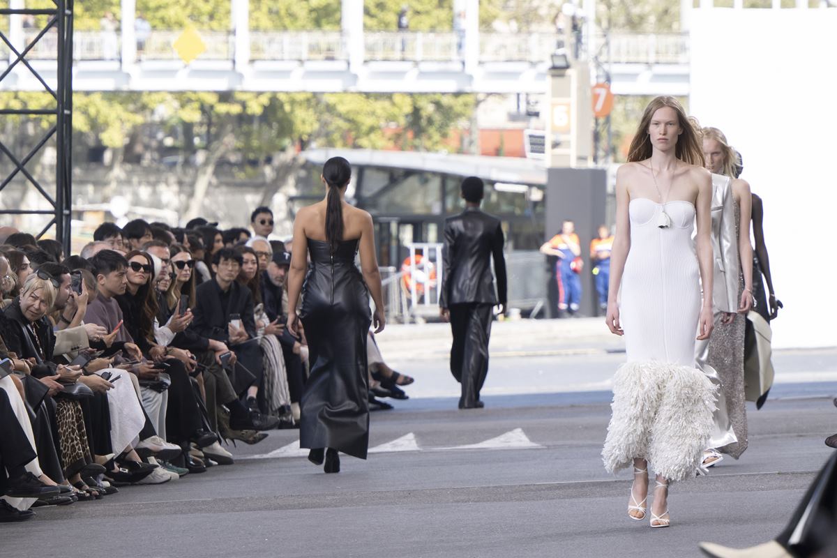 Passarela de moda. À direita, modelo de frente usando look branco. À esquerda, modelo de costas usando look preto - Metrópoles