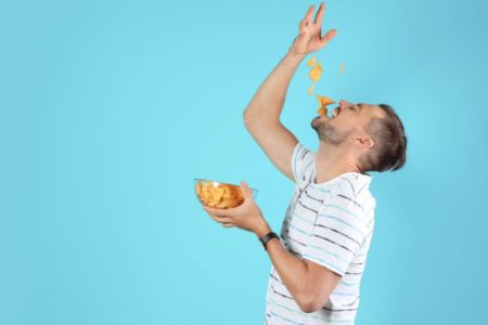 homem comendo gulosamente umas batatas chips