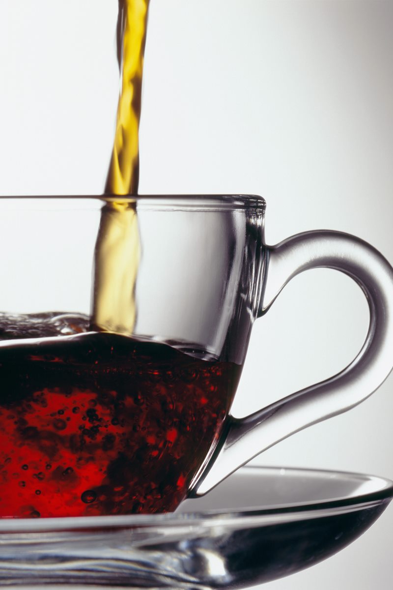 Imagem mostra uma xícara transparente com chá preto, É possível ver também que estão colocando mais chá na xícara - Metrópoles