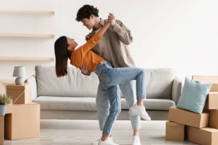 casal dançando no meio da sala em mudança e caixas no chão