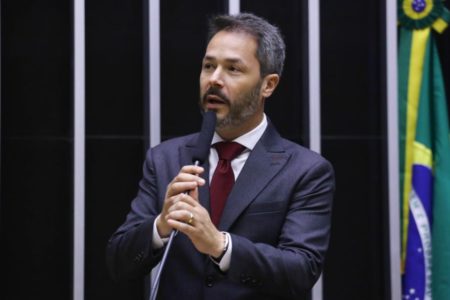 Fotografia colorida mostra Saulo, um homem grisalho e com barba, segurando um microfone no plenário da Câmara dos Deputados - Metrópoles