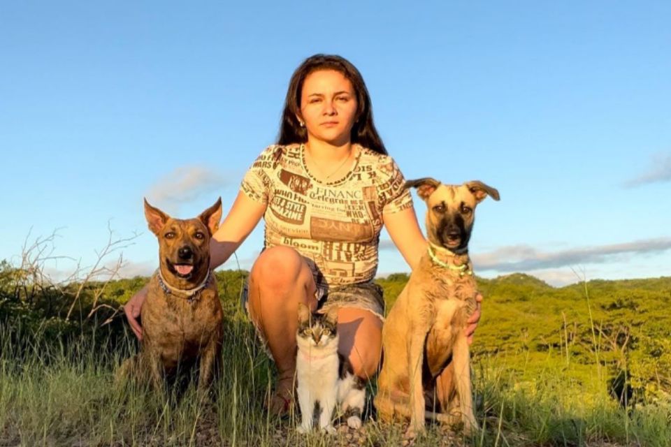 Foto colorida de uma mulher com três animais - Metrópoles