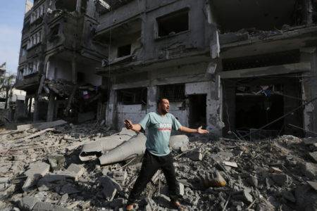 Um residente gesticula em torno de edifícios destruídos e destroços no bairro de Al-Karama após um ataque aéreo israelense que dura cinco dias na Cidade de Gaza