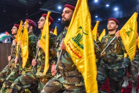 Imagem colorida mostra combatentes do Hezbollah segurando bandeiras do grupo islâmico - Metrópoles