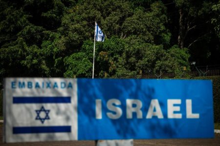 Imagem colorida mostra bandeira de Israel e placa, em frente à embaixada do país - Metrópoles