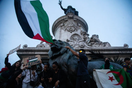 Imagem colorida mostra manifestante francês segurando uma bandeira da Palestina - Metrópoles