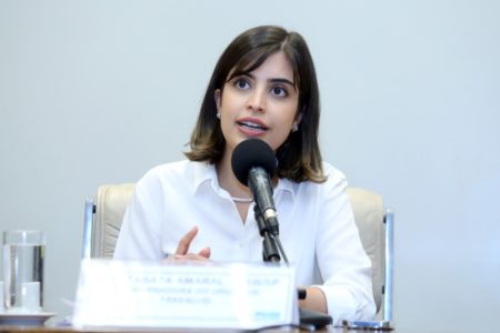 Imagem colorida mostra Tabata Amaral, mulher branca de cabelo castanho, de camisa branca, falando ao microfone sentada em uma sala de debates da Câmara - Metrópoles
