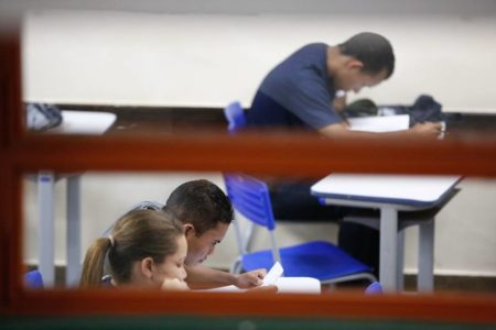 Foto colorida mostrando pessoas em aula escrevendo em apostilas para o Enem - Metrópoles