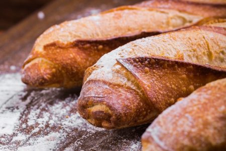 Três pães grandes em mesa com resto de farinha branca - Metrópoles