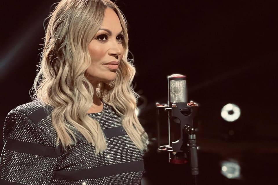 Solange Almeida posa ao lado de um microfone e com um look brilhante - Metrópoles