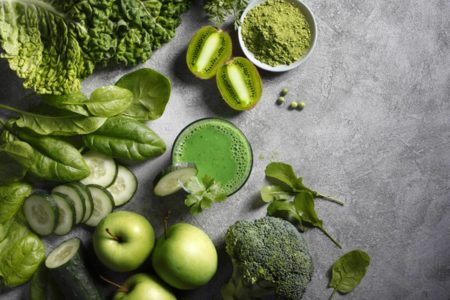 Imagem colorida superior de suco detox cercado de ingredientes verde, entre eles a caouve - Metrópoles