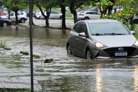 Imagem colorida de carro passando em uma rua alagada de Santa Catarina chuvas - Metrópoles