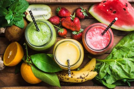 Foto colorida de três sucos detox ao redor de frutas - Metrópoles